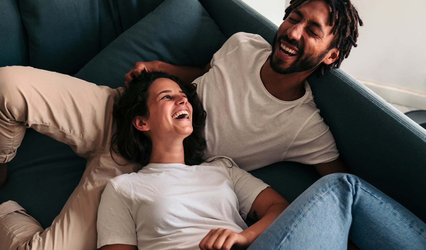 Living Begins Here lifestyle image of a couple embracing and laughing on a large couch